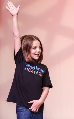A child raises their hand to ask a question during one of Village Theatre's school programs.